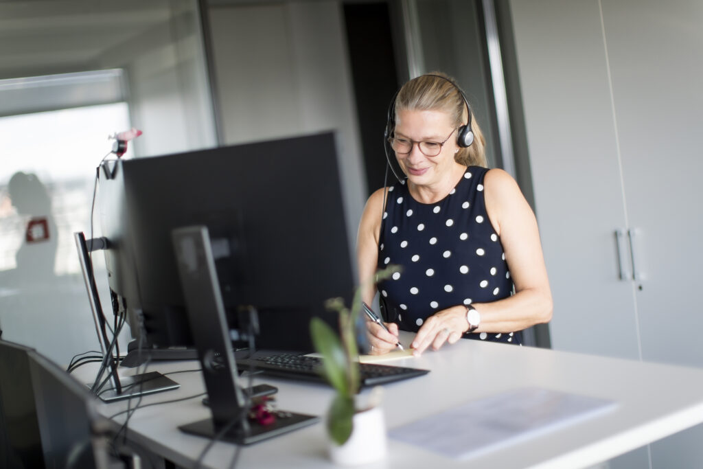 Eine innovas-Mitarbeitende telefoniert und macht sich Notizen.