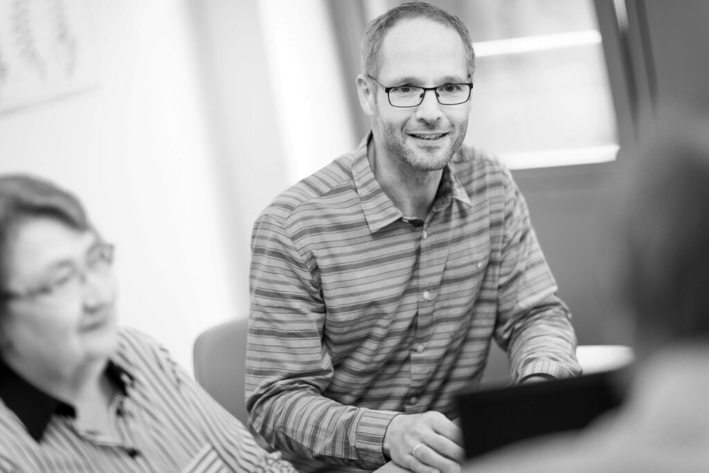 Ein innovas-Mitarbeitender ist im Gespräch mit anderen Mitarbeitenden.