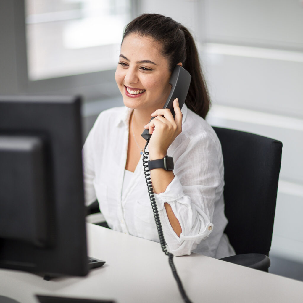 Eine innovas-Mitarbeitende sitz an ihrem Arbeitsplatz und telefoniert.