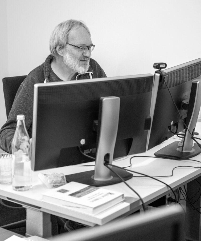 Ein innovas-Mitarbeiter sitzt an seinem Schreibtisch und arbeitet an seinem PC mit zwei Monitoren