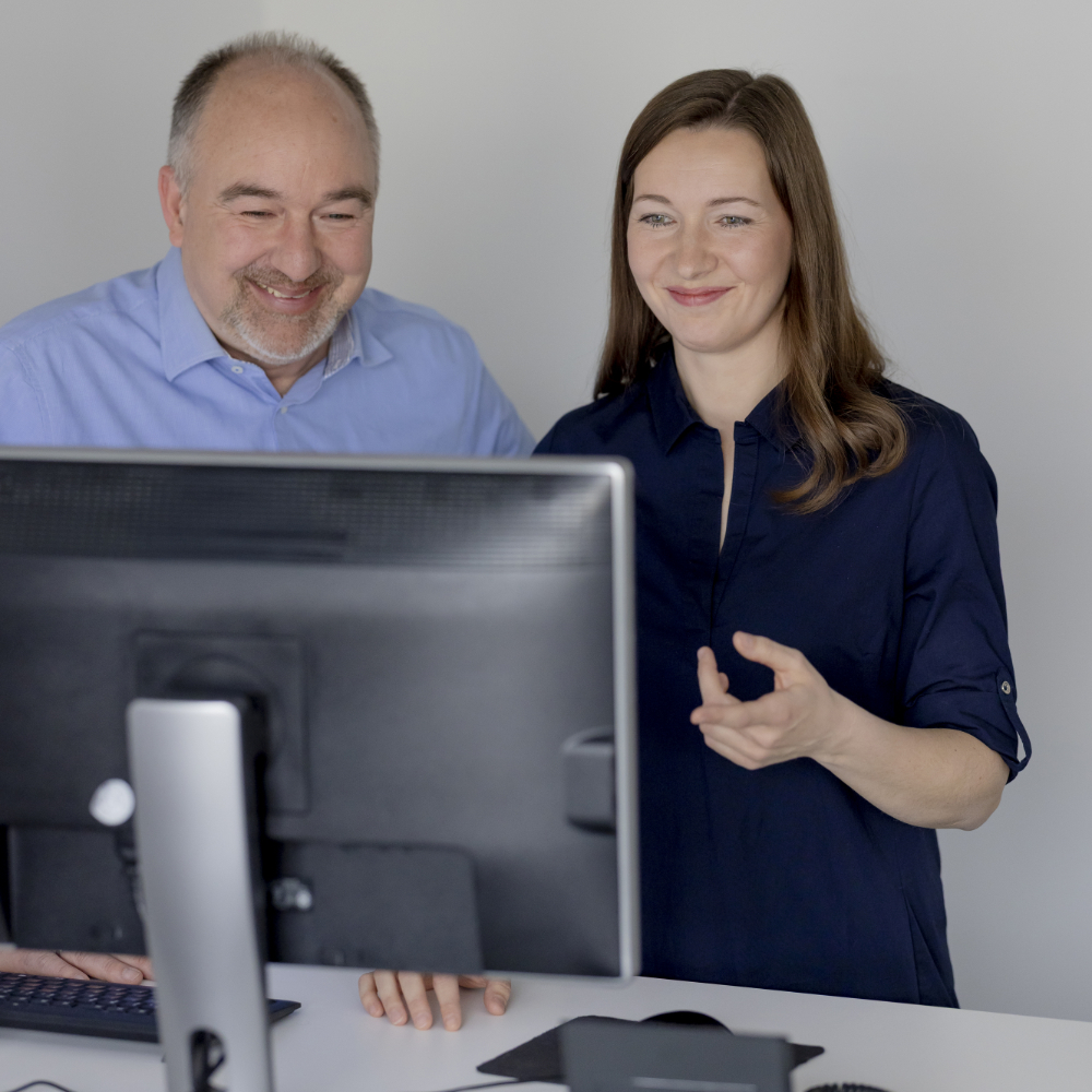 Zwei innovas-Mitarbeitende im Gespräch vor einem Monitor.
