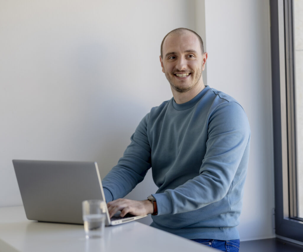 Ein innovas-Mitarbeitender steht an einem Laptop.