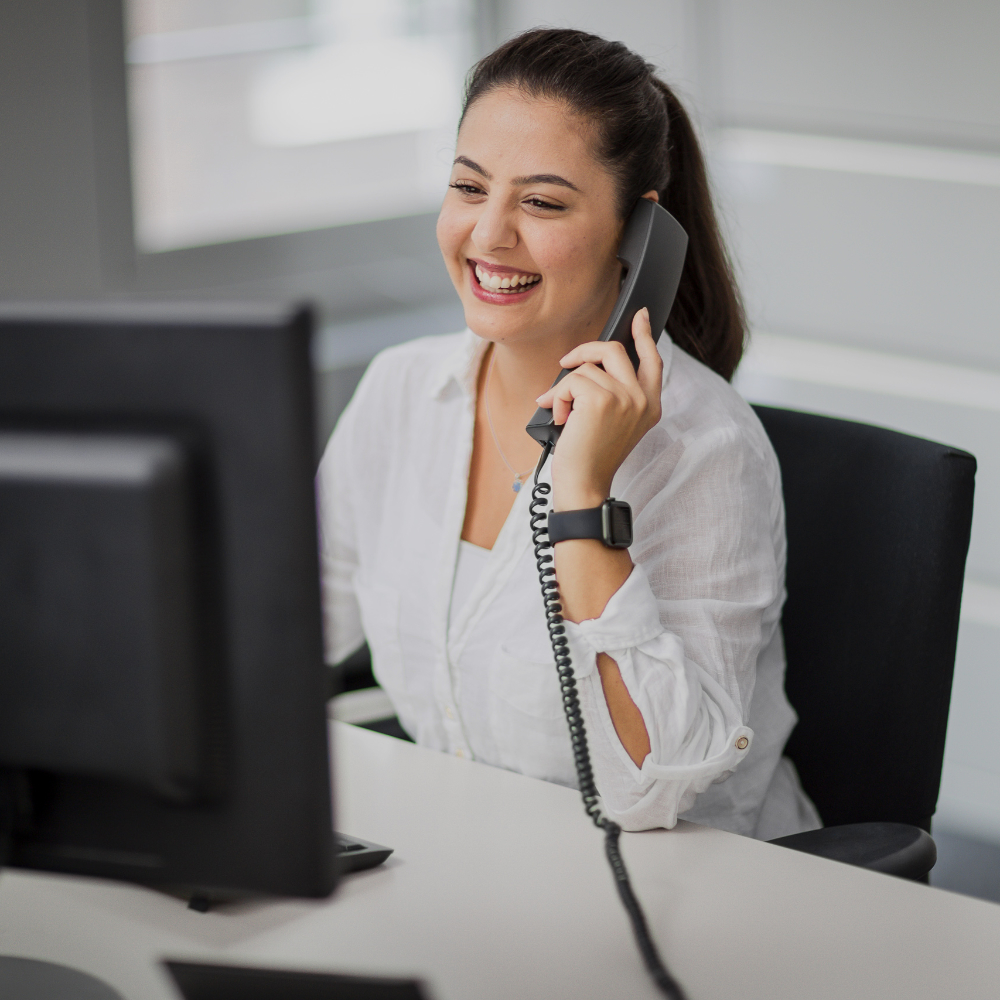 Eine innovas-Mitarbeitende sitzt an ihrem Arbeitsplatz und telefoniert.