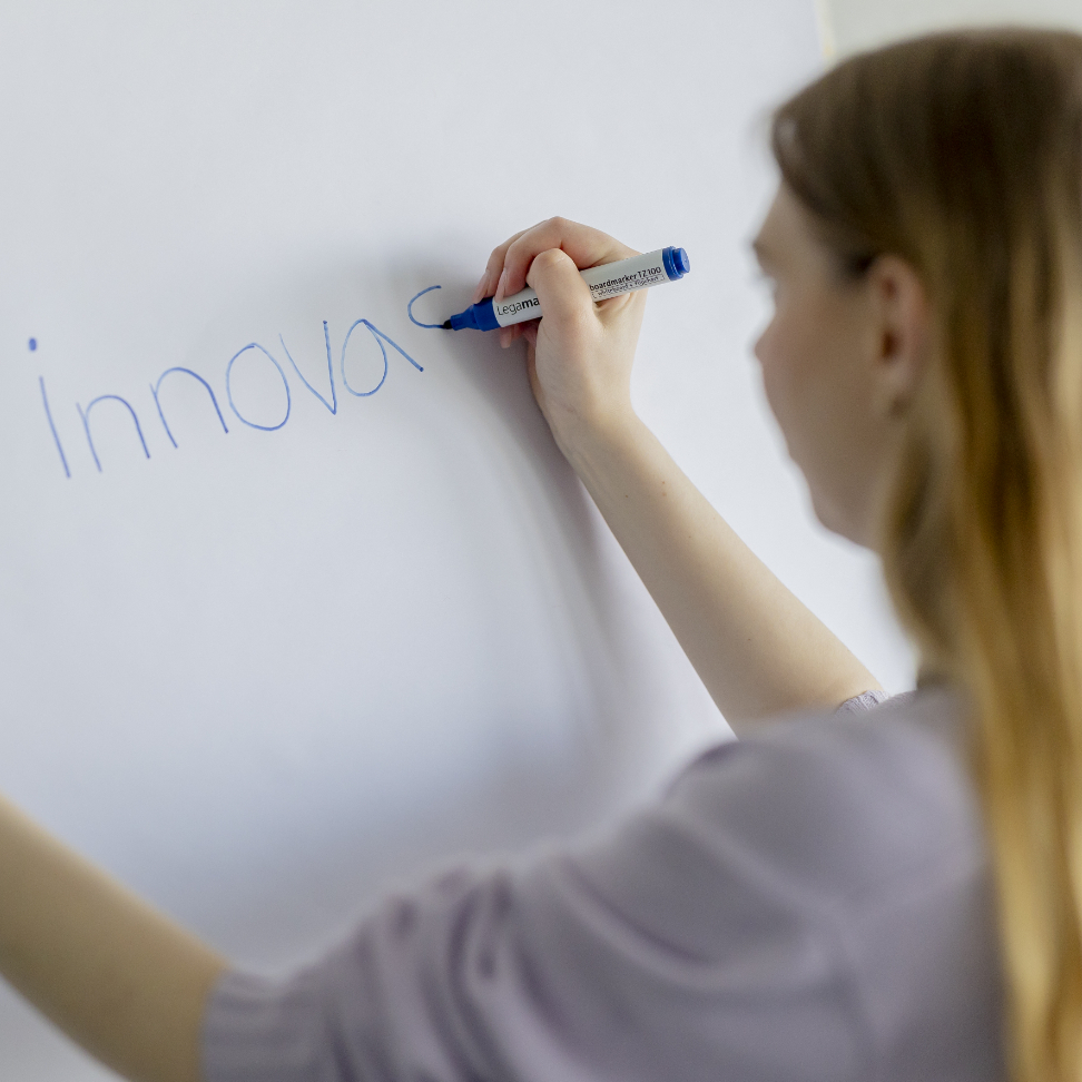 Eine innovas-Mitarbeitende steht vor einem Flipchart.