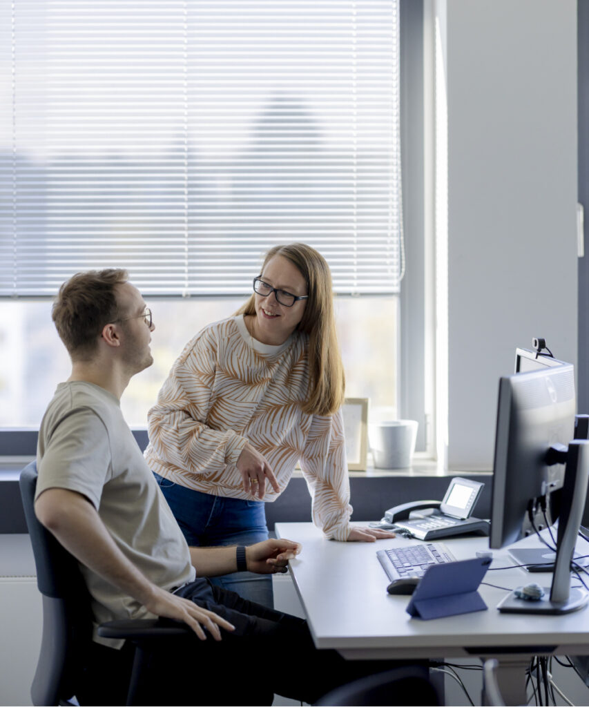 Zwei innovas-Mitarbeitende in einer Besprechungssituation am Arbeitsplatz.