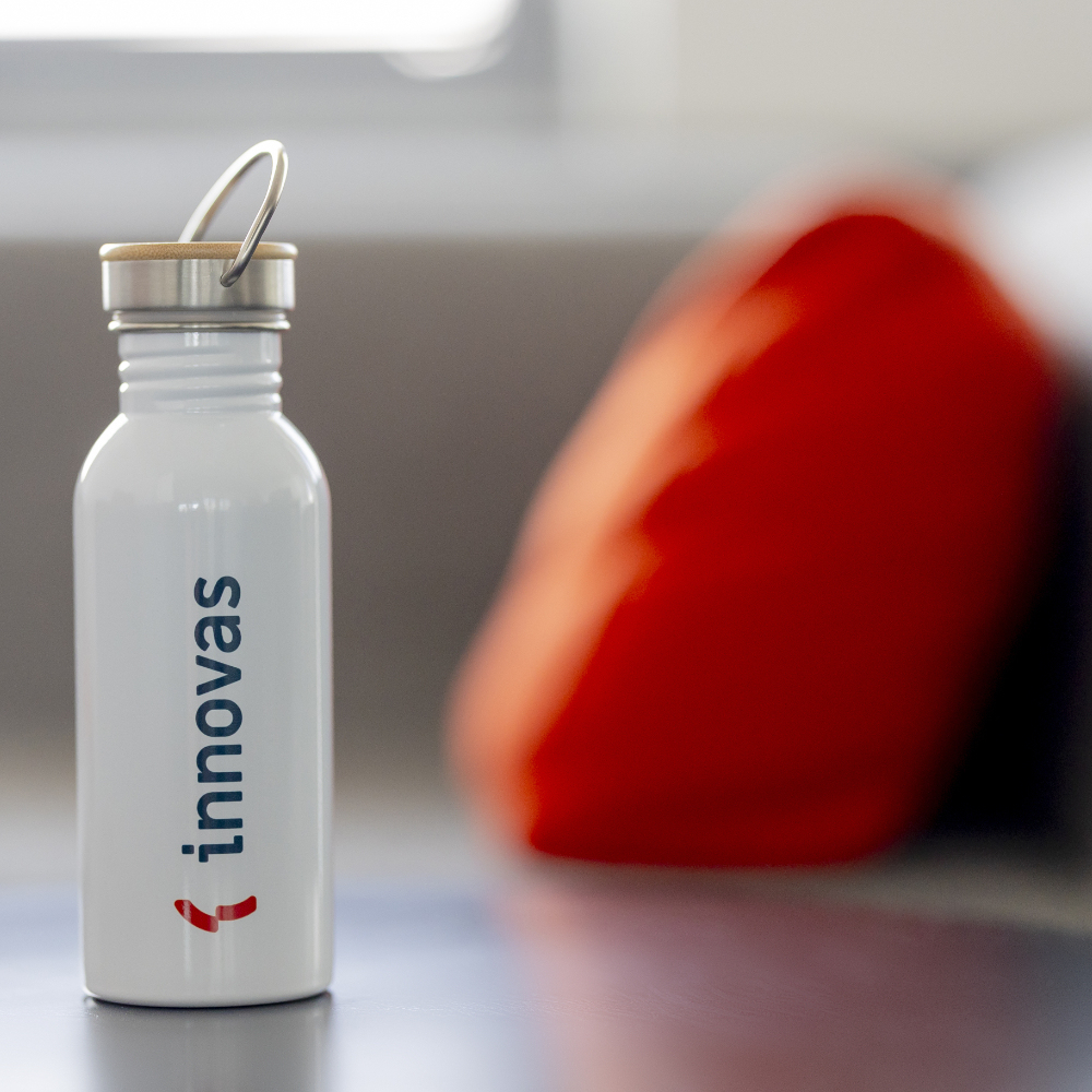 Eine Trinkflasche mit dem innovas-Logo steht im Vordergrund.