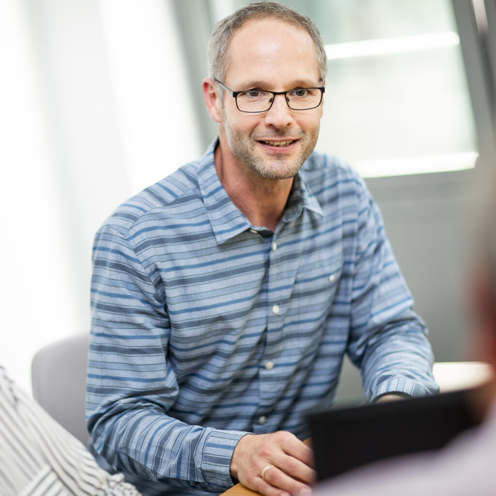 Ein innovas-Mitarbeitender ist im Gespräch mit anderen Mitarbeitenden.