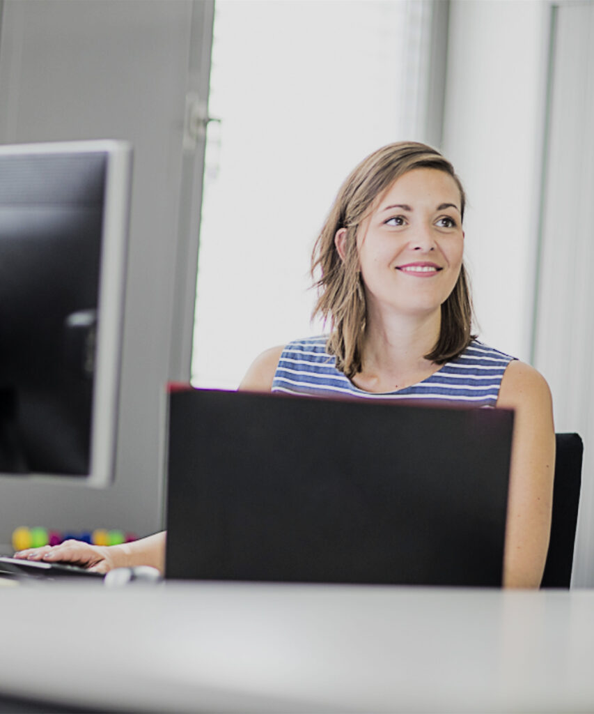 Eine innovas-Mitarbeitende sitzt an Ihrem Arbeitsplatz.
