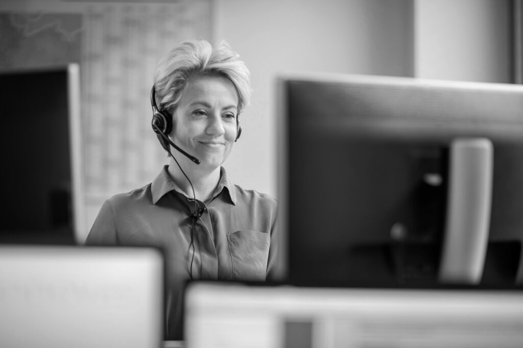 Eine innovas-Mitarbeiterin sitzt an ihrem Schreibtisch und telefoniert mit ihrem Headset