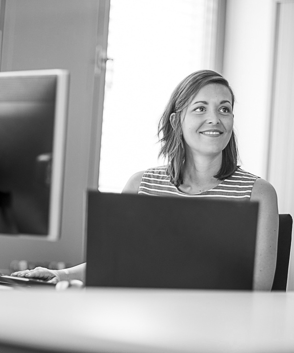 Eine innovas-Mitarbeitende sitzt an einem Schreibtisch vor einem Monitor