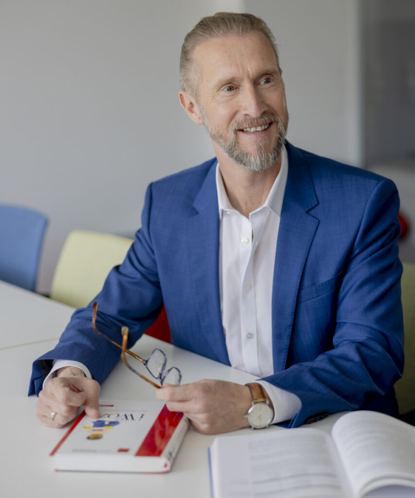 Ein innovas-Miotarbeitender sitzt mit Fachliteratur in einem Besprechungsraum.