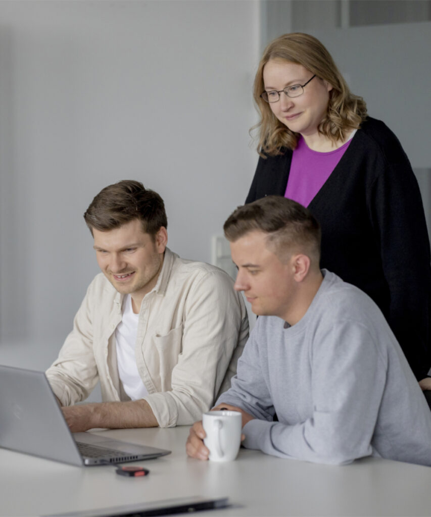 Drei innovas-Mitarbeitende schauen gemeinsam auf einen Laptop.