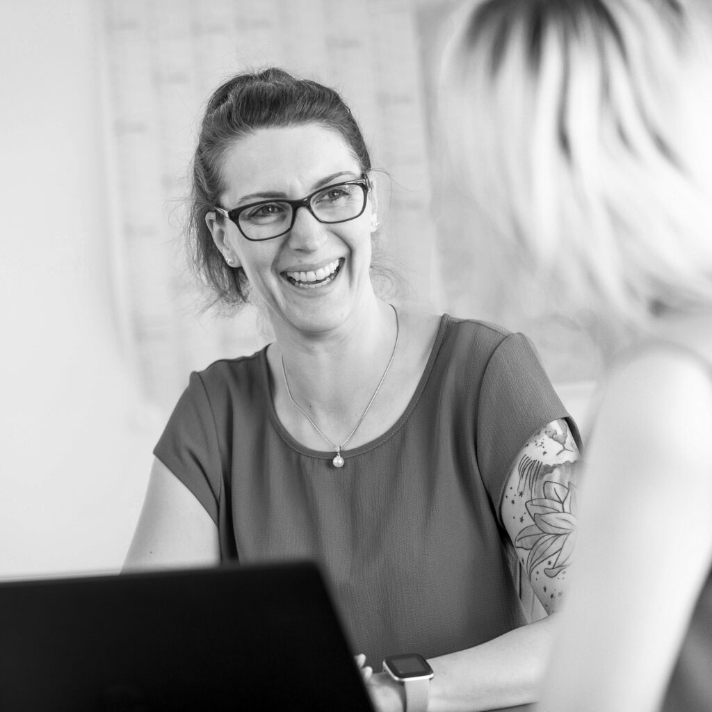 Eine innovas-Mitarbeitende lächelt ihre Gesprächspartnerin an