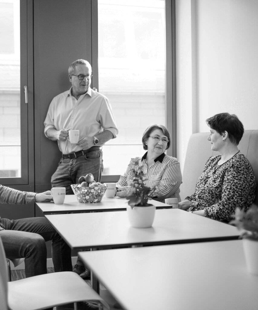 Vier innovas-Mitarbeitende sprechen im Aufenthaltsraum miteinander